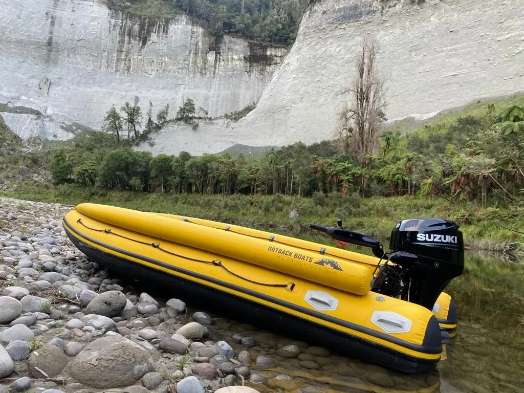 A yellow boat is in the water near some rocks.