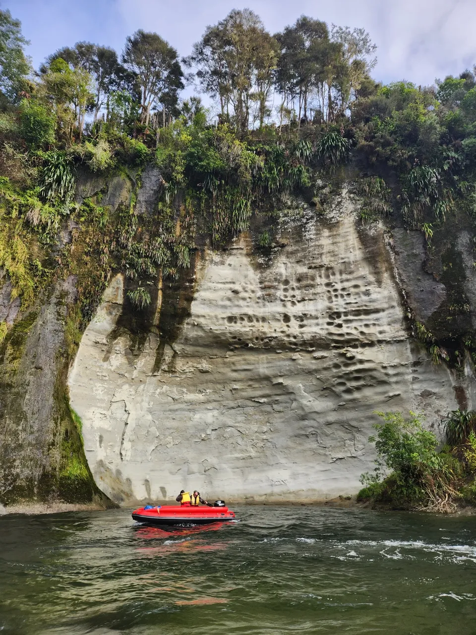 A boat is in the water near some rocks.