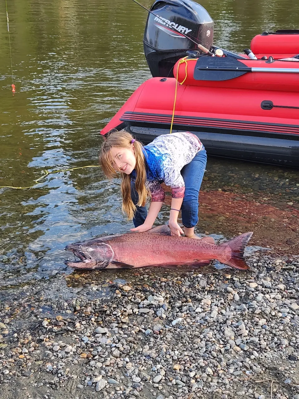 A little girl holding onto a fish in the water