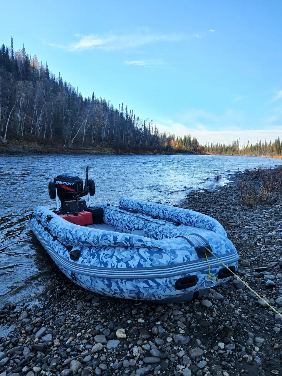 A boat is sitting on the shore of a river.