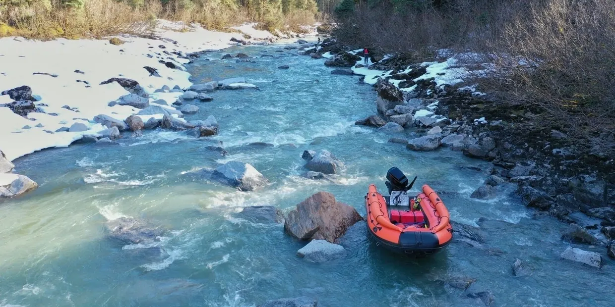 A man in an orange raft floating down the river.