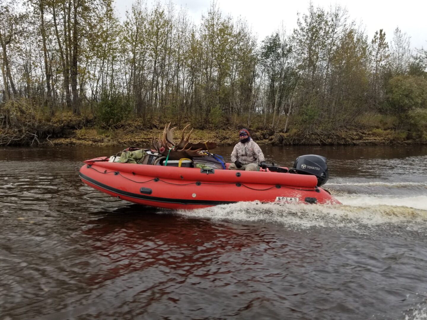 A man riding on the back of a red boat.